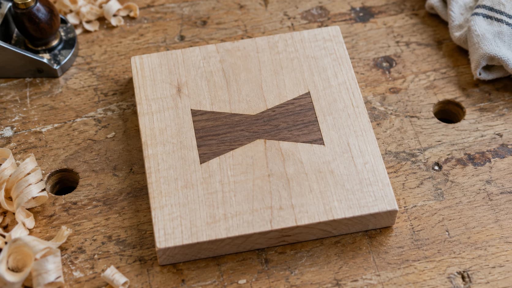A flush walnut bow-tie inlay fitted into a maple sample panel