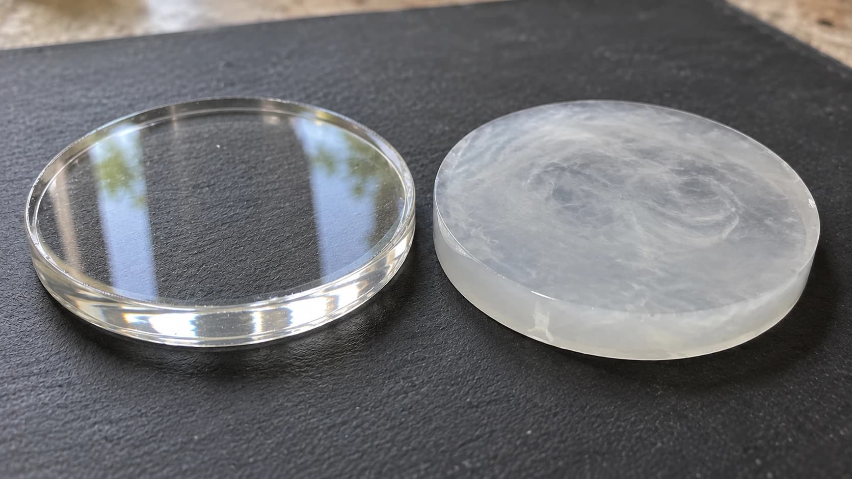 Clear and cloudy resin discs side by side on the same charcoal work mat