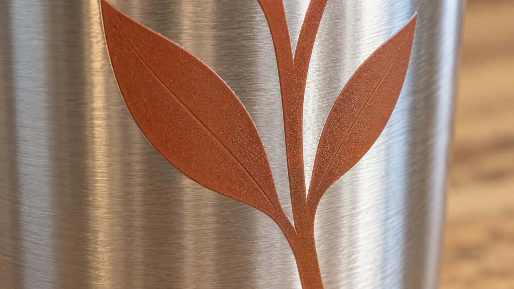 Terracotta vinyl leaves following the curve of a stainless tumbler