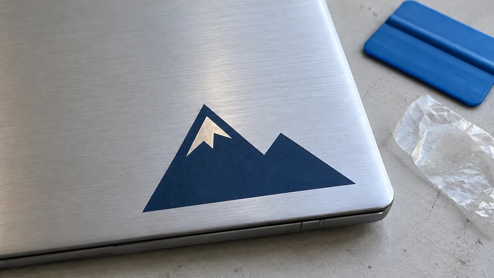 Thin navy mountain decal with a silver snow gap on a laptop lid