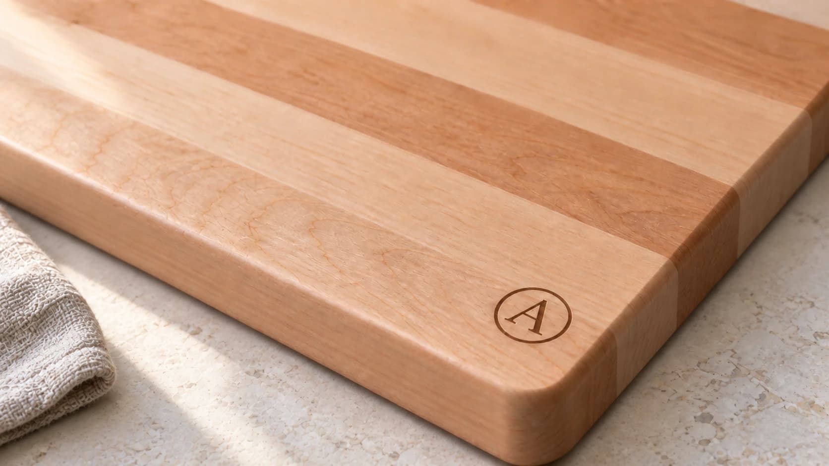 Close-up of a small circular A engraved near the rounded corner of a maple board