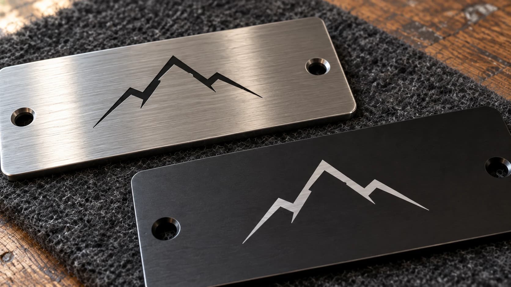 Close-up comparing a dark mountain mark on brushed steel with a pale mark on a black metal plate