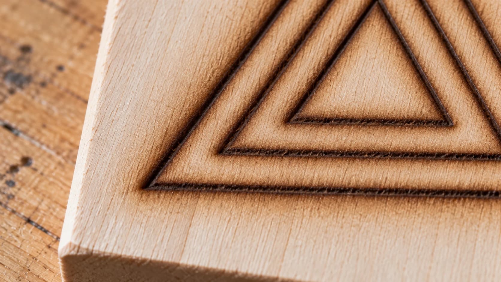 Smoke haze surrounding shallow engraved triangle outlines on basswood