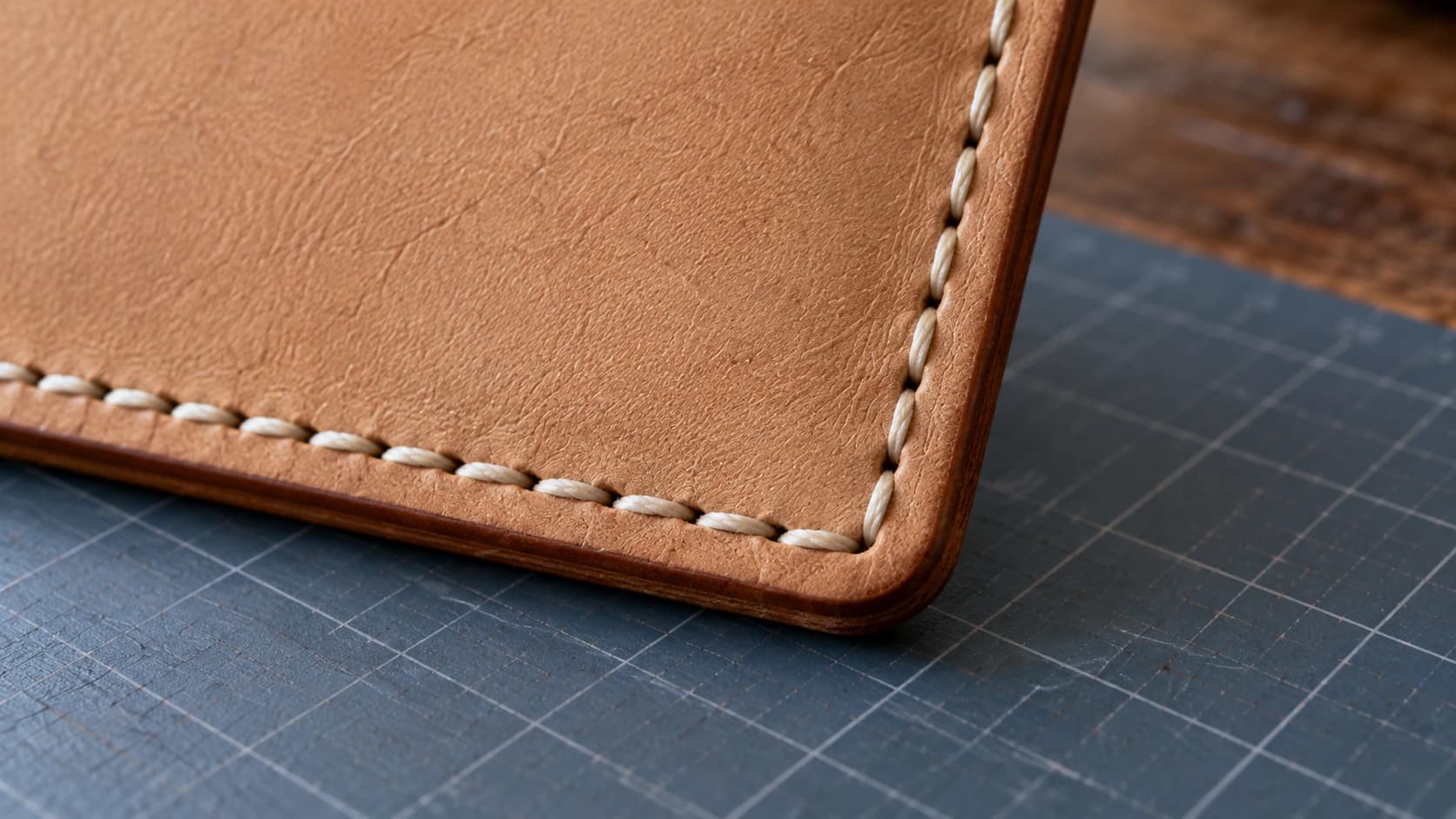 Cream stitches passing through the tan card holder’s aligned edges