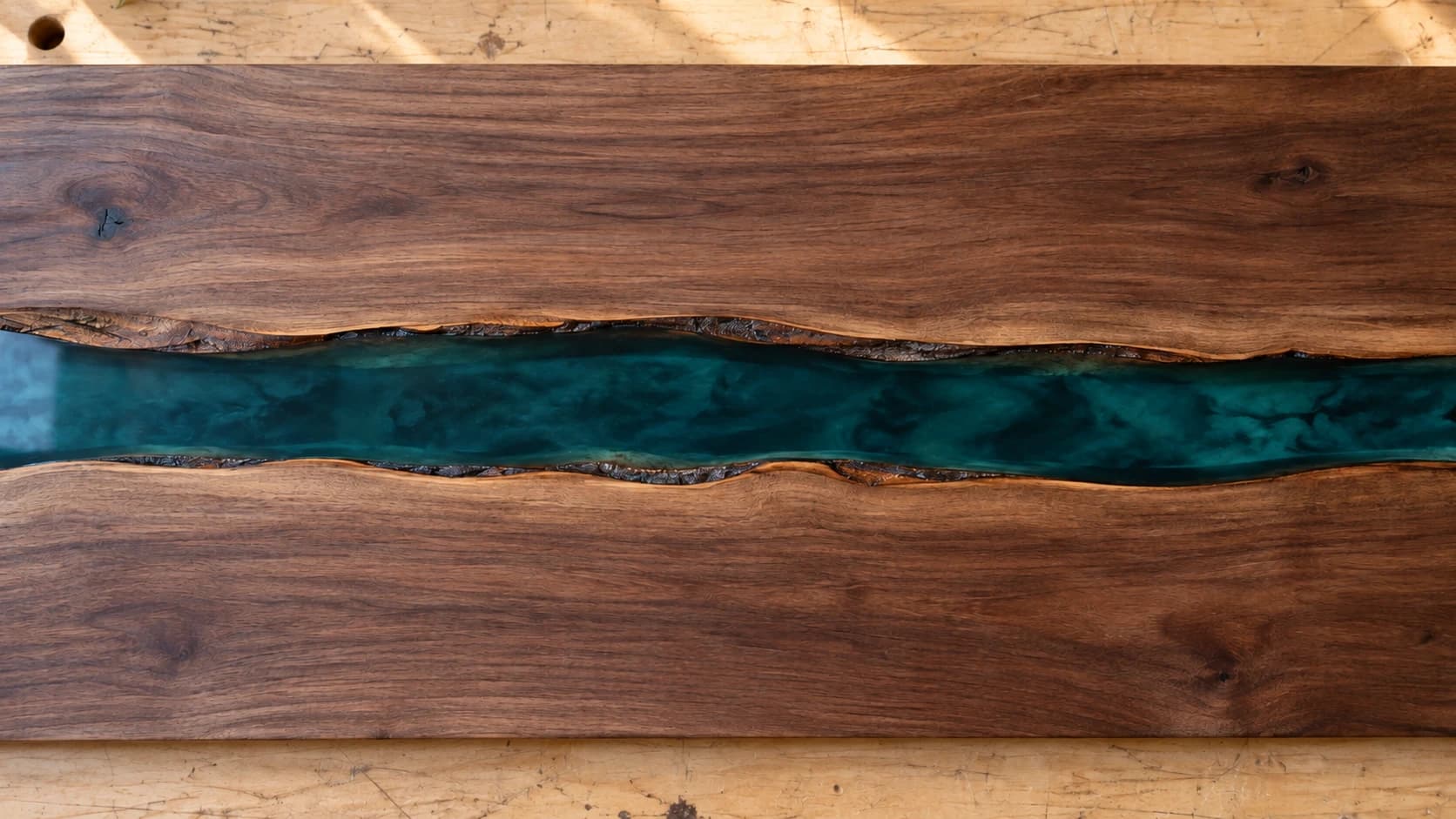 Close view of the same walnut grain and teal resin along both live-edge boundaries